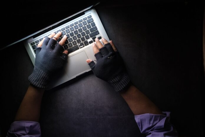 Persona con guantes negros usando un MacBook